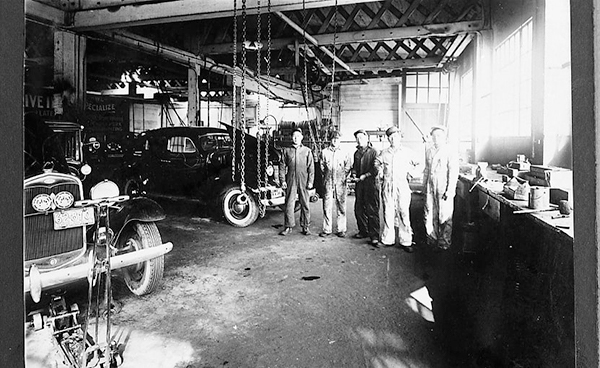 a group of men stand inside Maikawa Nippon Auto Supplies garage