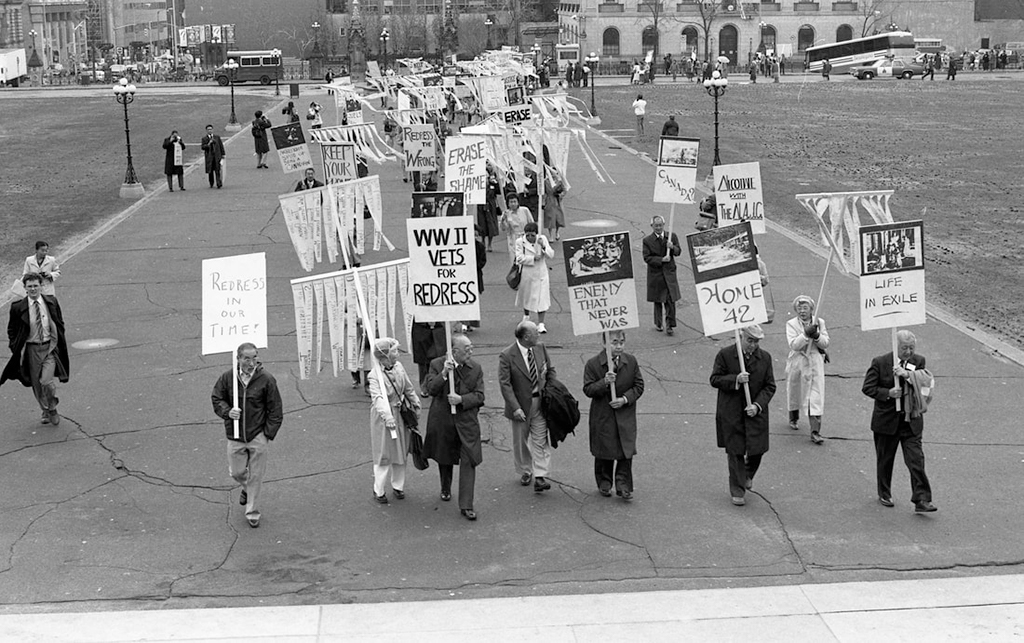 a group of people marching holding signs supporting redress