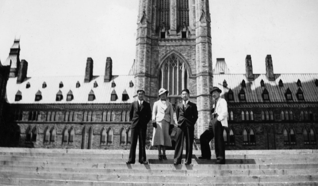 Four people pose in front of parliament hill