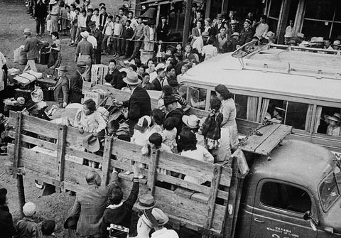 Image of truck with woman and children in the back being transported to internment