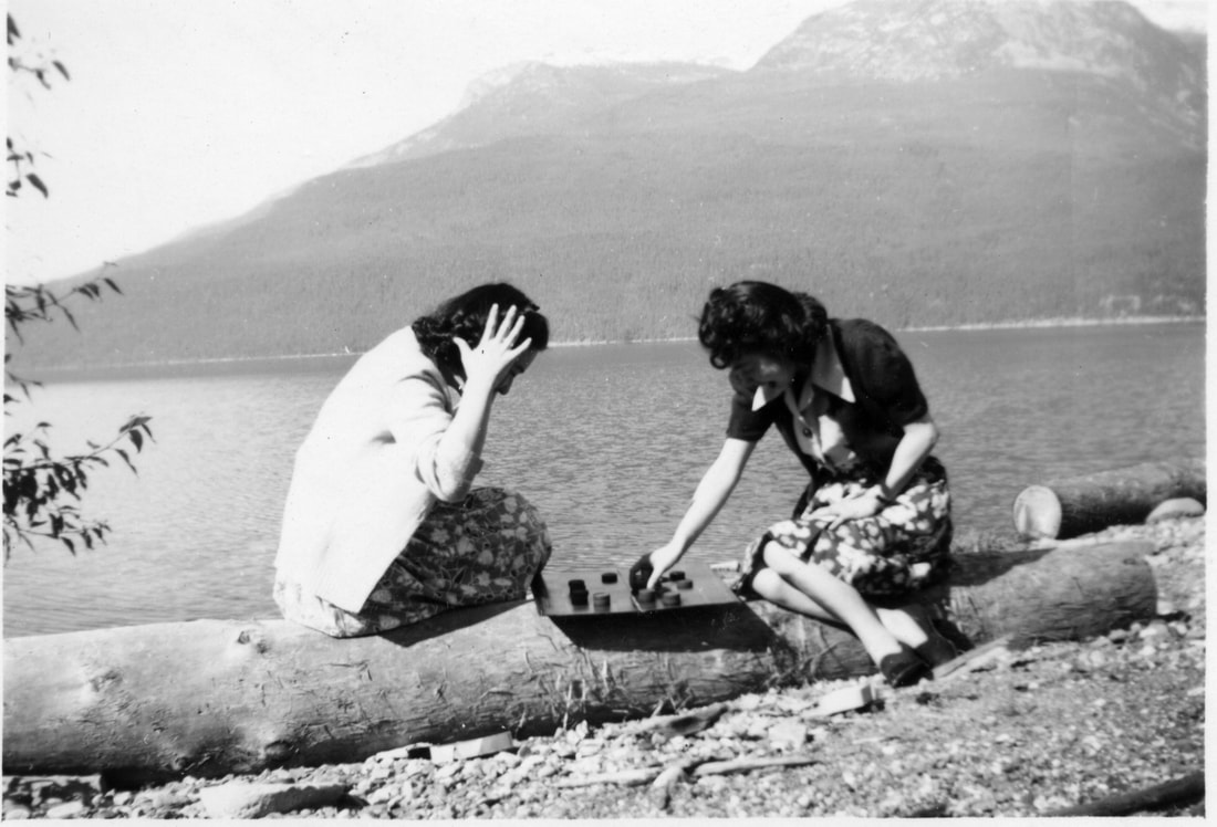 Two women play checkers outside at an internment camp