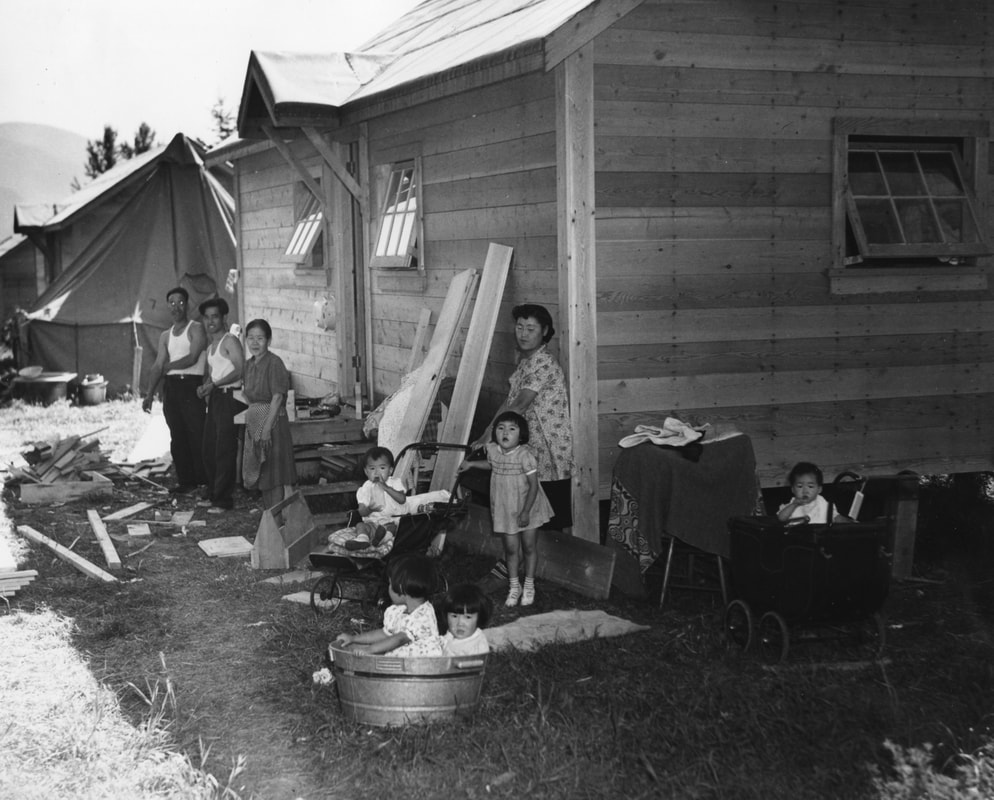 Japanese-Canadian families standing outside internment shacks