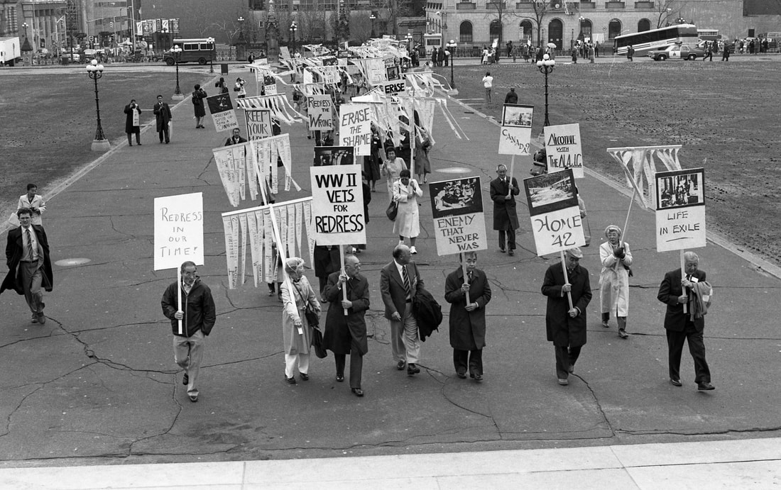 A group marches carrying signs supporting redress